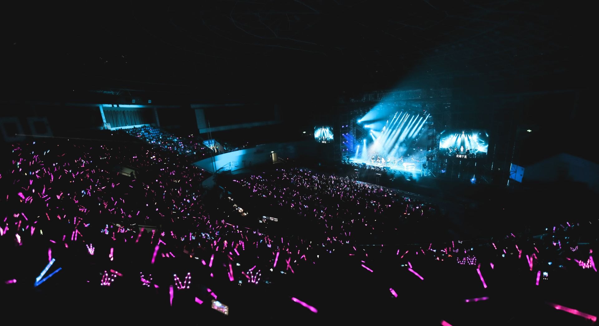 A concert crowd holding glowing blue light sticks (illustrative photo)